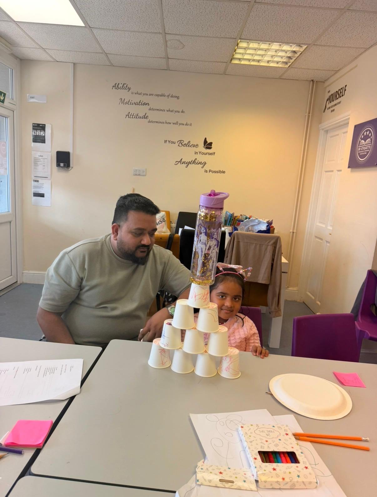 A father and child with their cup pyramid creation